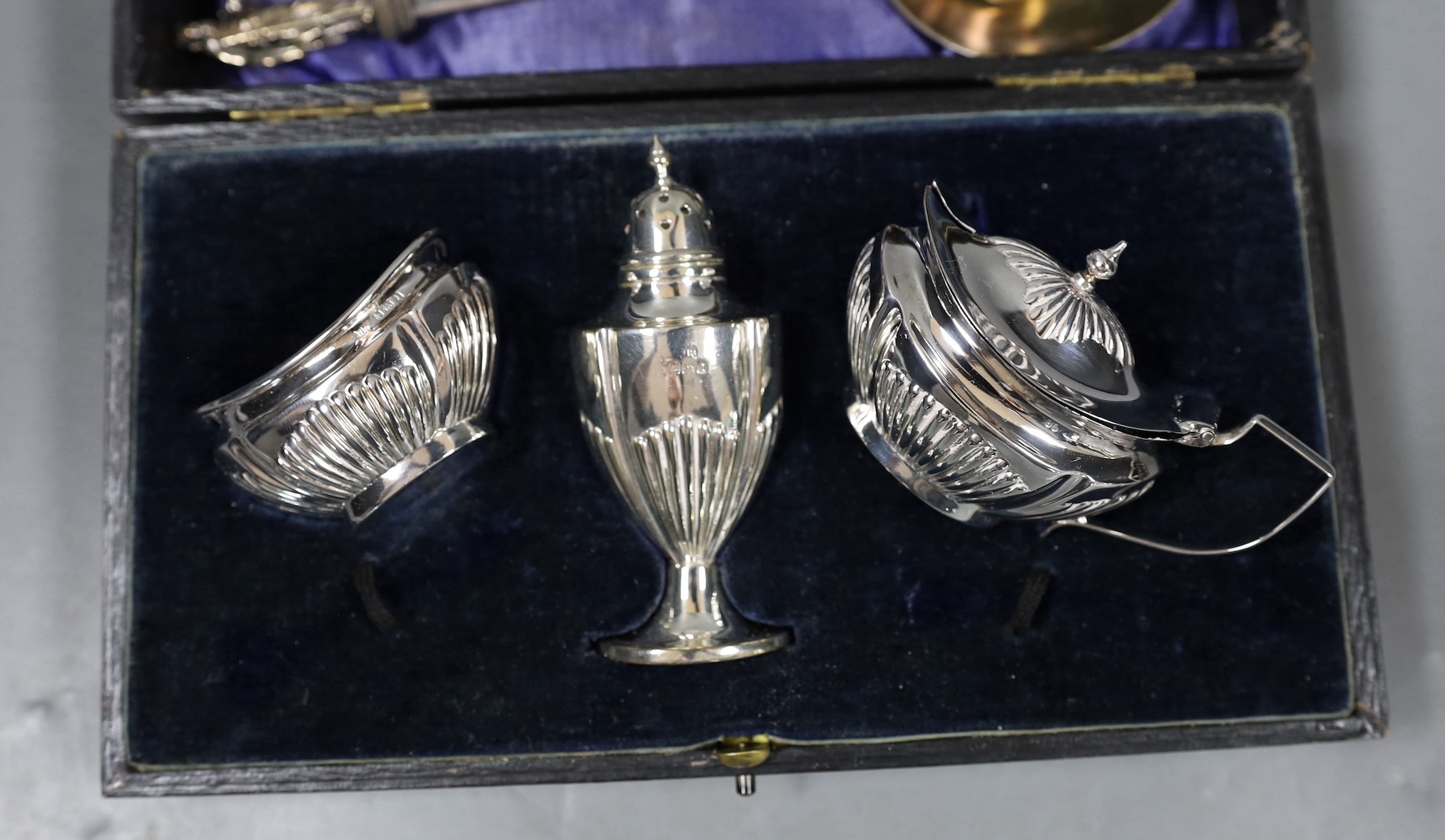 A cased George V silver three piece condiment set, lacking spoons, a 1930's Arts & Crafts sile r spoon by Liberty & Co, a Victorian silver apostle spoon and a pair of 18th century silver sugar nips.